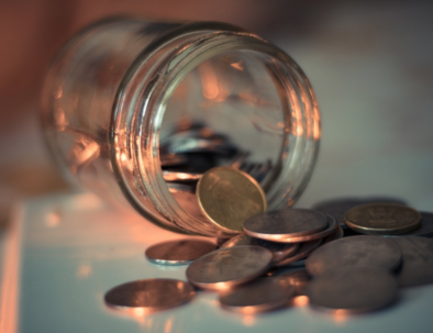 Image of a glass jar lying on its side with coins falling out