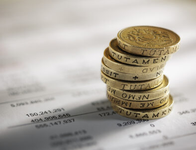 Stack of pound coins on financial figures balance sheet